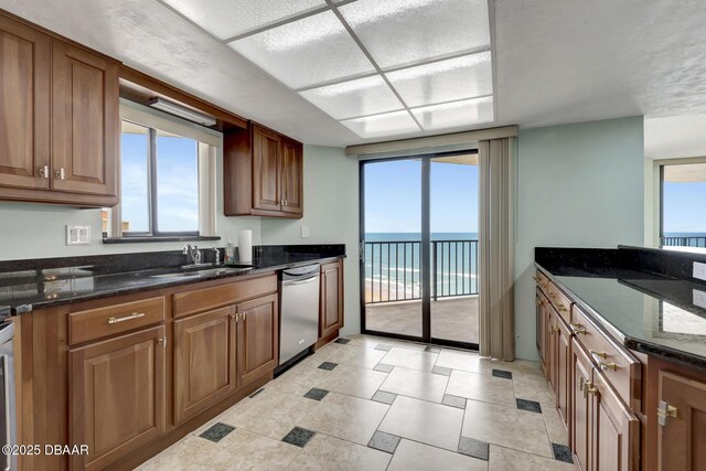 2425 S Atlantic Ave Unit 801, Daytona Beach Shores, FL 32118 - kitchen featuring a sink, stainless steel dishwasher, a water view, dark stone counters, and plenty of natural light