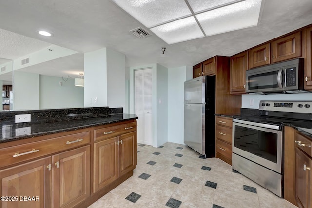 2425 S Atlantic Ave Unit 801, Daytona Beach Shores, FL 32118 - kitchen with stainless steel appliances, dark stone counters, and brown cabinets