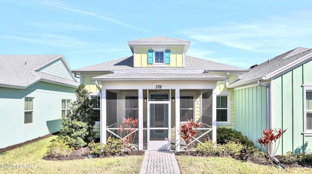 back of house featuring board and batten siding, a sunroom, and a shingled roof