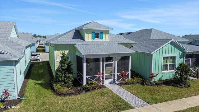 bungalow with a sunroom, a shingled roof, a front lawn, and board and batten siding