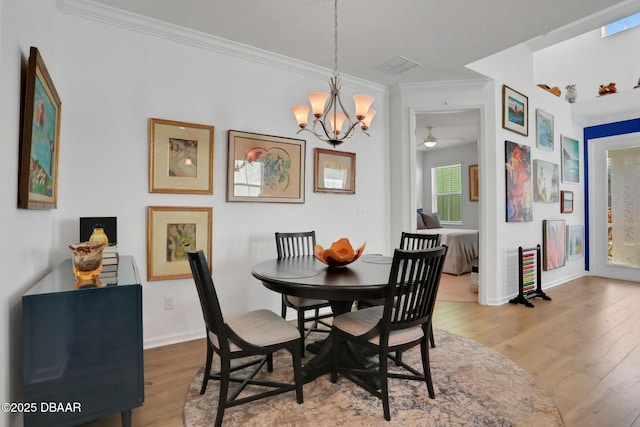 dining room featuring a notable chandelier, wood finished floors, visible vents, baseboards, and crown molding