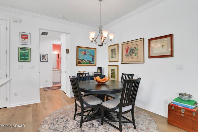 dining room featuring visible vents, baseboards, light wood-style flooring, an inviting chandelier, and crown molding