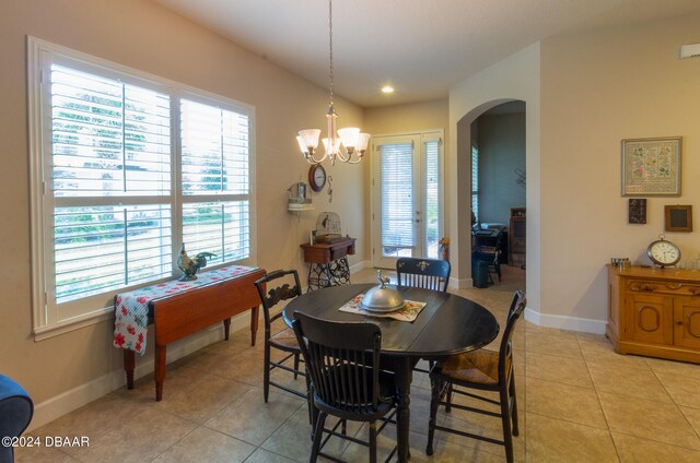 tiled dining space featuring a wealth of natural light and an inviting chandelier