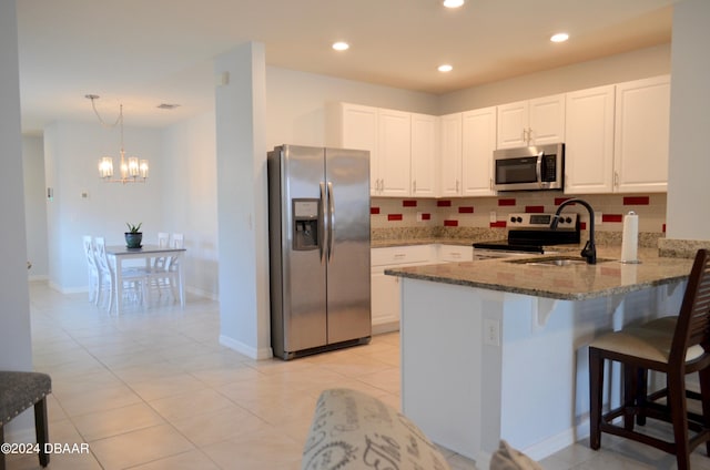 kitchen featuring stainless steel appliances, kitchen peninsula, dark stone counters, white cabinets, and decorative backsplash