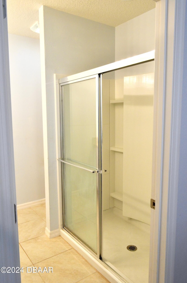 bathroom featuring walk in shower, tile patterned floors, and a textured ceiling