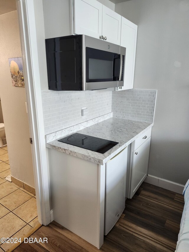 kitchen featuring white cabinets, dark wood-type flooring, black electric cooktop, and tasteful backsplash