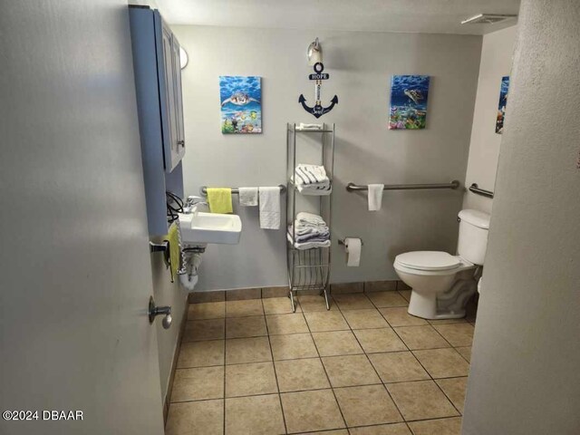 bathroom with toilet, sink, and tile patterned flooring