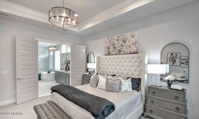 carpeted bedroom featuring an inviting chandelier, ensuite bath, and a raised ceiling