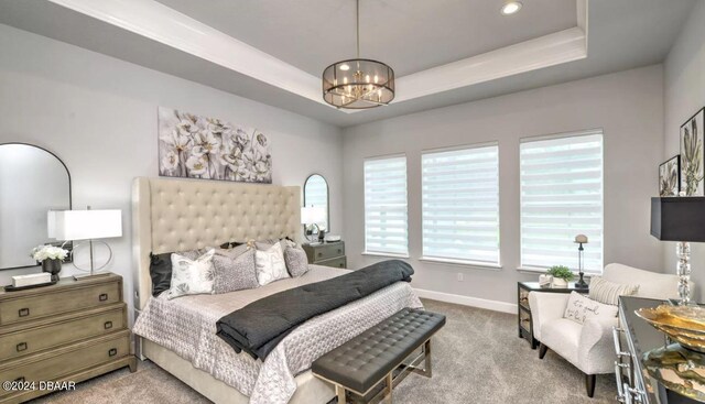 bedroom featuring light carpet, an inviting chandelier, and a tray ceiling