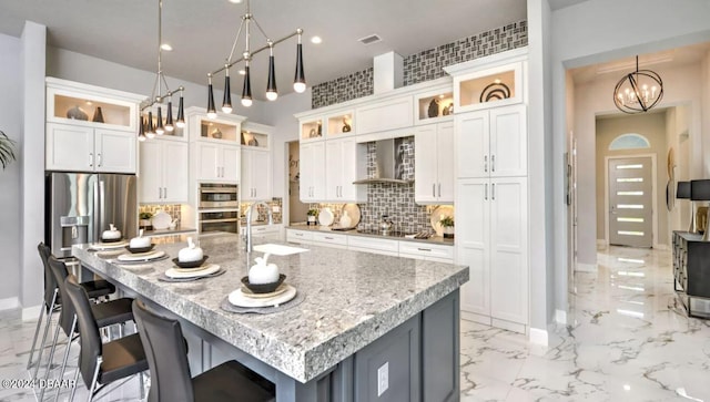 kitchen with wall chimney exhaust hood, sink, a breakfast bar, and a kitchen island with sink