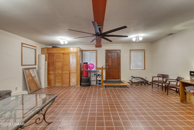 sitting room with ceiling fan, a textured ceiling, and tile patterned flooring