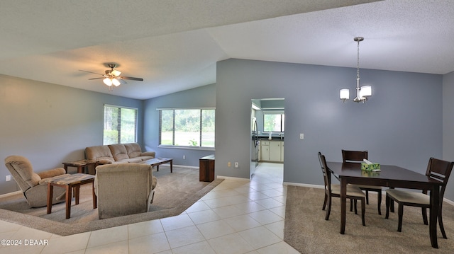 interior space featuring ceiling fan with notable chandelier, light tile patterned floors, and vaulted ceiling