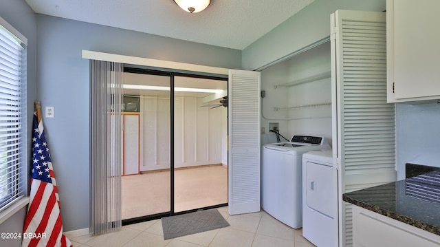 laundry room featuring a textured ceiling, light tile patterned floors, a healthy amount of sunlight, and washer and dryer