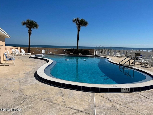 view of pool with a water view and a patio