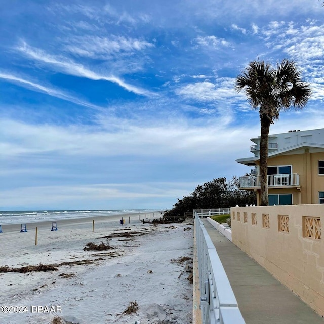 exterior space with a water view, a beach view, and a balcony