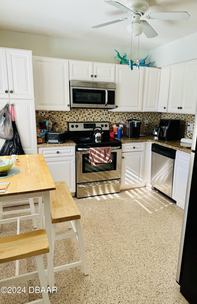 kitchen featuring white cabinets, ceiling fan, appliances with stainless steel finishes, and tasteful backsplash