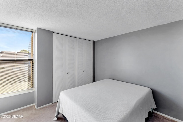 5500 Ocean Shore Blvd Unit 58, Ormond Beach, FL 32176 - bedroom featuring light colored carpet, multiple windows, a closet, baseboards, and a textured ceiling