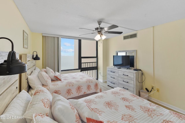 bedroom with a wall of windows, ceiling fan, and light wood-type flooring