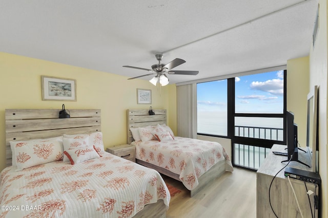 bedroom with floor to ceiling windows, ceiling fan, a textured ceiling, and light wood-type flooring