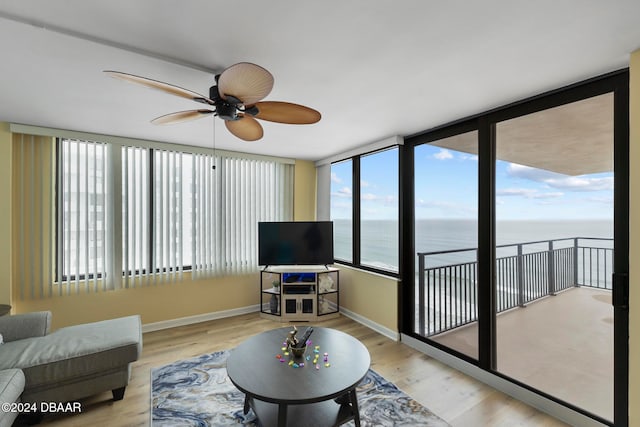 living room featuring expansive windows, light hardwood / wood-style floors, and ceiling fan