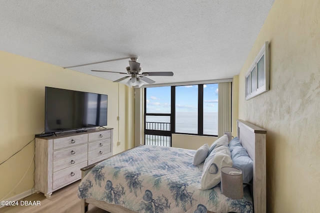 bedroom featuring a textured ceiling, ceiling fan, light hardwood / wood-style floors, and floor to ceiling windows