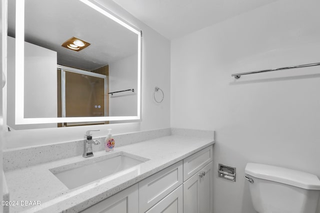 bathroom featuring vanity, an enclosed shower, and toilet