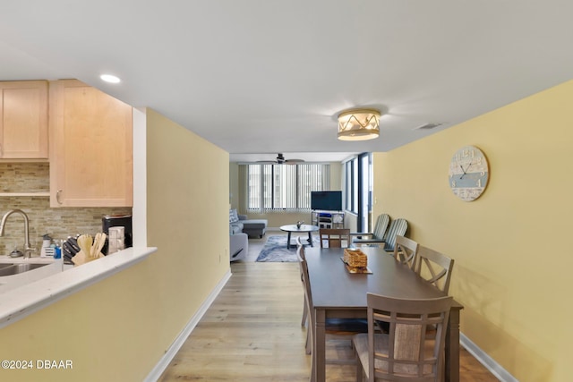 dining area with ceiling fan, light hardwood / wood-style floors, and sink