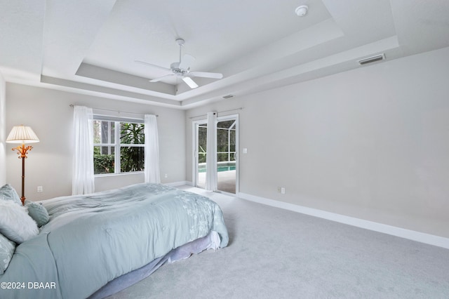 bedroom featuring access to exterior, carpet flooring, a raised ceiling, and ceiling fan