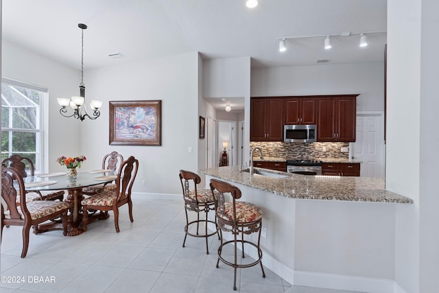 kitchen featuring pendant lighting, sink, light stone countertops, a notable chandelier, and stainless steel appliances