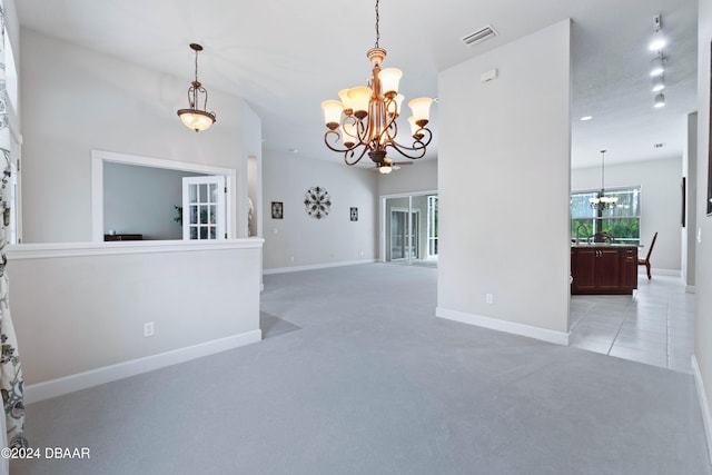 carpeted empty room featuring rail lighting and a notable chandelier