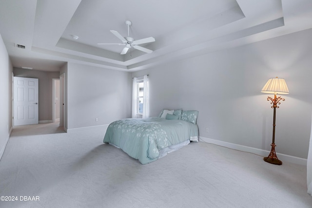 bedroom featuring ceiling fan, light carpet, and a tray ceiling