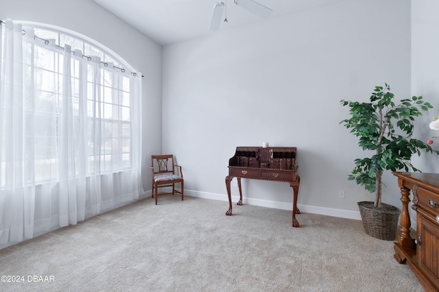 living area featuring light colored carpet and ceiling fan