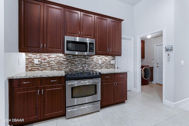 kitchen featuring light stone counters, light tile patterned floors, stainless steel appliances, and washer / clothes dryer