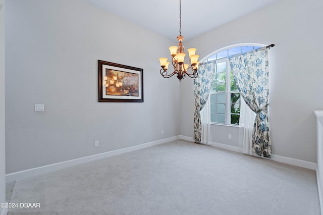 carpeted spare room with a chandelier