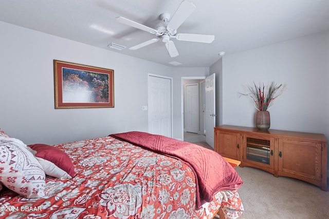 bedroom with ceiling fan, light colored carpet, and a closet