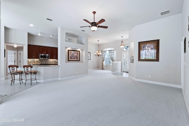 unfurnished living room featuring light colored carpet and ceiling fan with notable chandelier