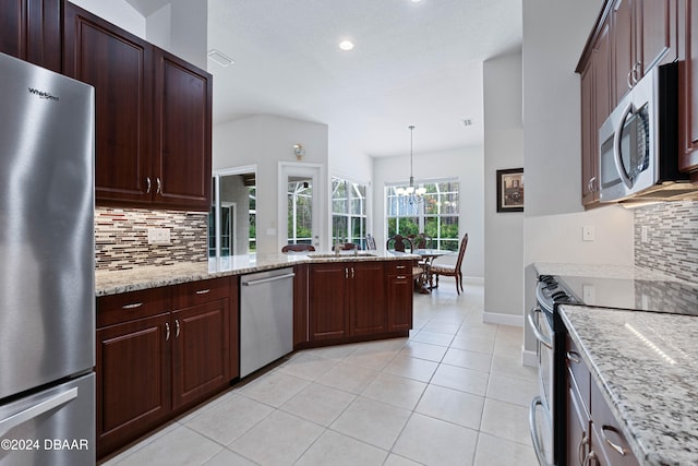 kitchen featuring light stone countertops, backsplash, stainless steel appliances, and hanging light fixtures