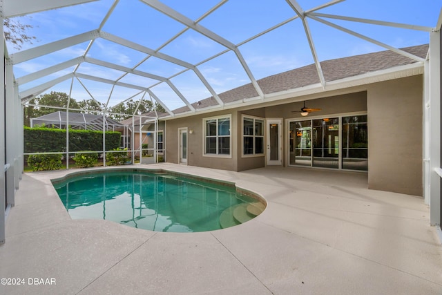 view of pool featuring glass enclosure, ceiling fan, and a patio