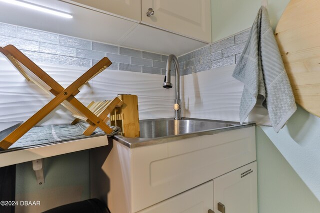 830 Maralyn Ave, New Smyrna Beach, FL 32169 - kitchen view of stainless steel counters, tasteful backsplash, a sink, and white cabinetry