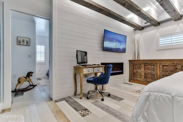 bedroom featuring a fireplace, beamed ceiling, and light hardwood / wood-style flooring