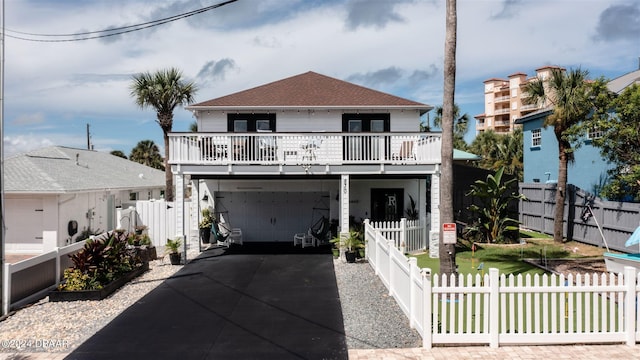 830 Maralyn Ave, New Smyrna Beach, FL 32169 - coastal inspired home featuring concrete driveway, a balcony, a fenced front yard, and a shingled roof