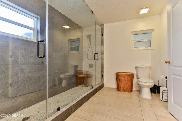 bathroom featuring toilet, wood-type flooring, and a shower with shower door