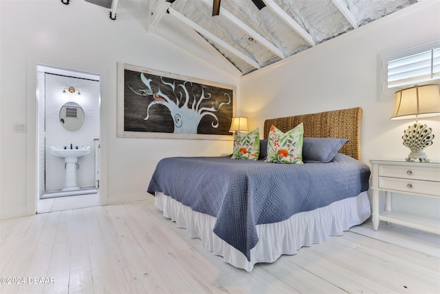 bedroom featuring lofted ceiling with beams, wood-type flooring, and ensuite bath