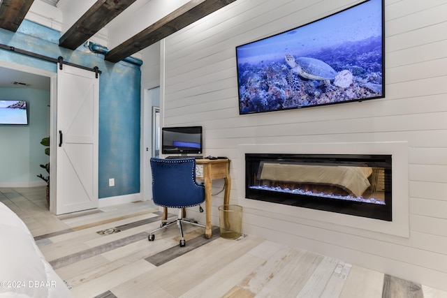 home office with a barn door, hardwood / wood-style flooring, and beam ceiling