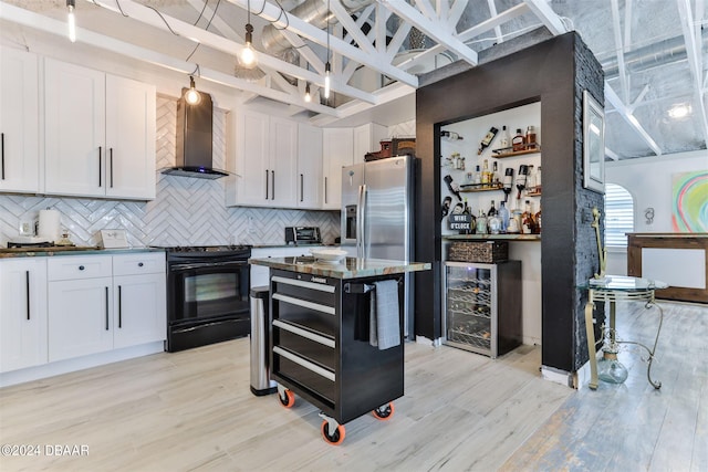 kitchen with light hardwood / wood-style floors, wall chimney exhaust hood, white cabinetry, and black electric range oven