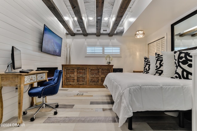 bedroom with light hardwood / wood-style floors and beam ceiling