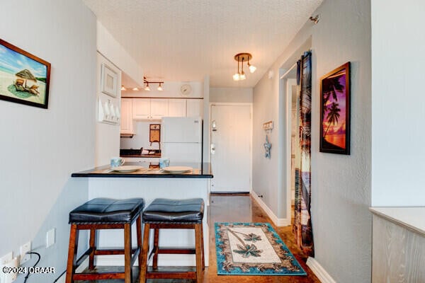 800 N Atlantic Ave Unit 516, Daytona Beach, FL 32118 - kitchen featuring freestanding refrigerator, a breakfast bar area, white cabinets, dark countertops, and a peninsula