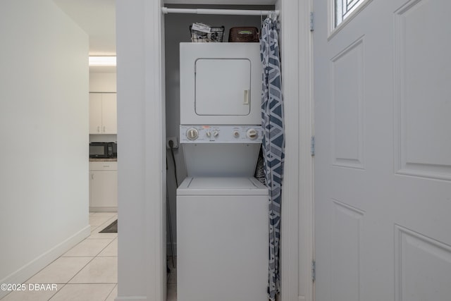 clothes washing area with stacked washer and dryer, laundry area, and light tile patterned flooring