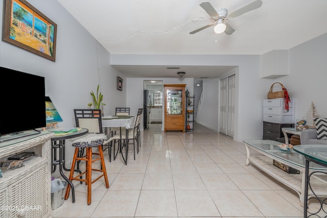 living room featuring light tile patterned floors, baseboards, and a ceiling fan