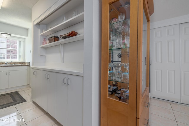 kitchen featuring light tile patterned floors, a textured ceiling, open shelves, white cabinets, and light countertops